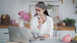 Portrait of beautiful woman makes makeup and use brush to put powder on her face