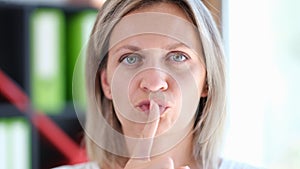 Portrait of beautiful woman making silence gesture with finger