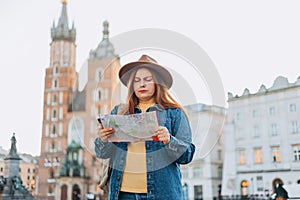 Portrait beautiful woman with paper map on urban street. Young worried female traveler lost in the city using map