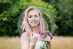 Portrait of a beautiful woman with pink hair and a clover bouquet, close-up