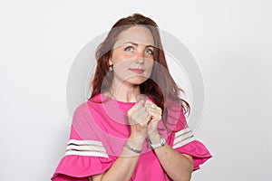 Portrait of a beautiful woman in a pink top with clenched fists looking up