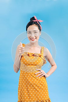 Portrait of a beautiful woman pinup retro style pointing at you smiling laughing isolated blue background wall. Body language,