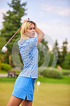 Portrait of a beautiful woman playing golf on a green field outdoors background. The concept of golf, the pursuit of