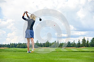 Portrait of a beautiful woman playing golf on a green field outdoors background. In full growth. Back vie. The concept