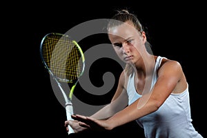 Portrait of beautiful woman playing tennis indoor. Isolated on black.
