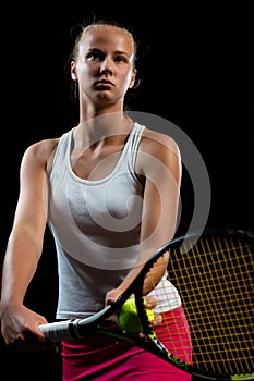 Portrait of beautiful woman playing tennis indoor. Isolated on black. photo