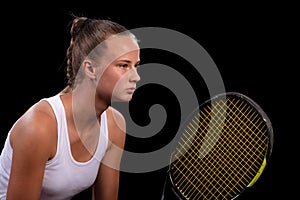 Portrait of beautiful woman playing tennis indoor. Isolated on black. photo