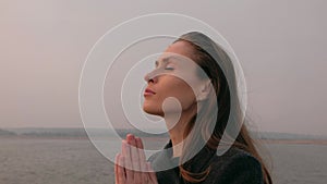 Portrait of beautiful woman praying in nature.