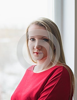 Portrait of a beautiful woman in a red dress in the window.