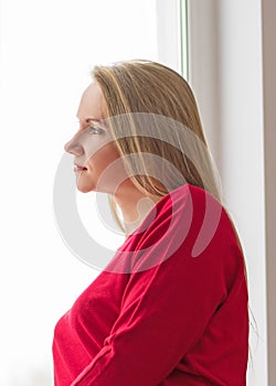 Portrait of a beautiful woman in a red dress in the window.