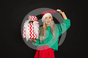 Portrait of beautiful woman in santa hat with toothy happy face, black background, copy space, studio shot, weared in green red
