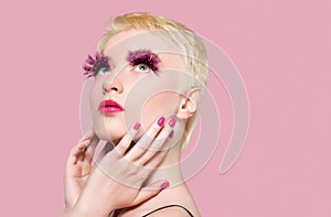 Portrait of a beautiful woman with short blonde hair, with false feather eyelashes, with pink manicure and pink lipstick on the