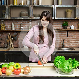 Portrait of beautiful woman slice, cutting tomato in the kitchen, cooking, prepare vegetable salad.