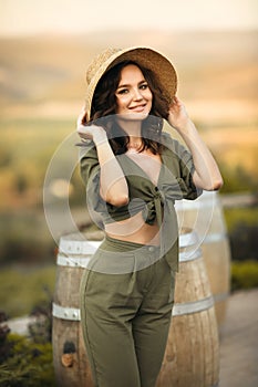 Portrait of beautiful woman smiling with curly hair in hat enjoying at park  by wooden barrel. Autumn Sunset photo