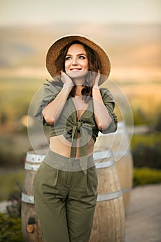 Portrait of beautiful woman smiling with curly hair in hat enjoying at park  by wooden barrel. Autumn Sunset photo