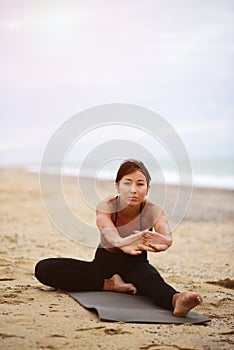 A portrait of beautiful woman stretching her arms and legs on the beach.