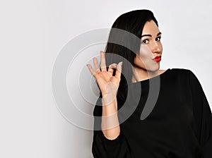 Portrait of beautiful woman in stylish casual clothing standing showing ok sign with fingers and looking at camera