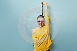 Portrait of a beautiful woman with sunglasses holding to the hair.  blue background.