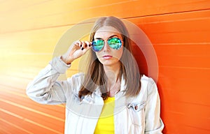 Portrait beautiful woman in sunglasses over colorful orange