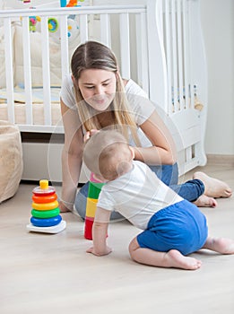 Portrait of beautiful woman teaching her baby boy how to assemble toy pyramid