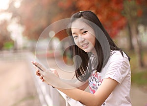 Portrait of a beautiful woman typing on the smart phone in a par