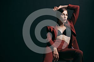 Portrait of a beautiful woman in an unbuttoned jacket and brassiere on a black background