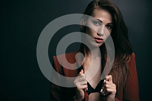 Portrait of a beautiful woman in an unbuttoned jacket on a dark background