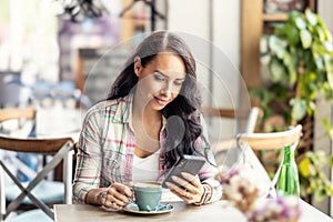 Portrait of beautiful woman using her smarphone in cafe, he reads received messages and follows social networks