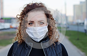 Portrait of a beautiful woman walking down the street wearing a protective mask to protect against infectious diseases. Attractive