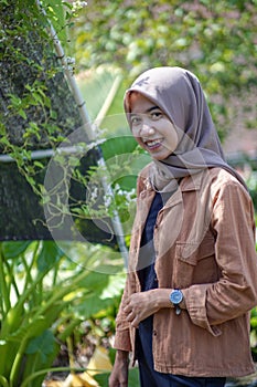 portrait of a beautiful woman wearing a modern hijab on the side of the greenhouse with a sweet smile