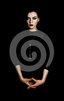 Portrait of a beautiful woman wearing red lipstick and an upside down religious cross, black background. photo