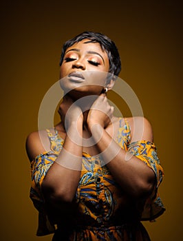 Portrait of a beautiful young African woman over yellow background. Studio picture