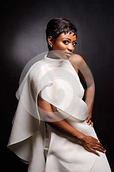 Portrait of a beautiful young African woman in white dress over black background