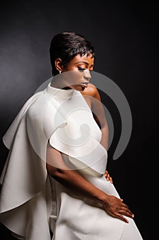 Portrait of a beautiful young African woman in white dress over black background