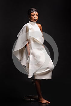 Portrait of a beautiful young African woman in white dress over black background