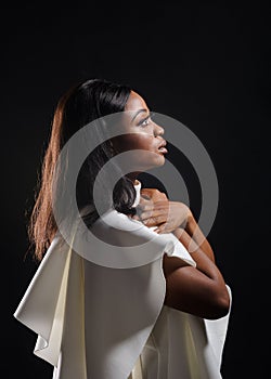 Portrait of a beautiful young African woman in white dress over black background