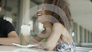 Portrait of beautiful young Afro American woman with friends at outdoor cafe.