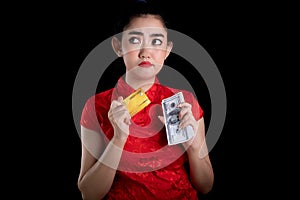 Portrait of a beautiful young Asia woman red dress traditional cheongsam holding credit card and money banknote 100 USD at the