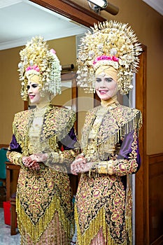 Portrait of beautiful young Asian muslim woman wearing traditional Minangkabau ethnic traditional dress standing by mirror