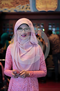 Portrait of beautiful young Asian muslim woman in wedding party with eyeglasses wearing pink dress and hijab
