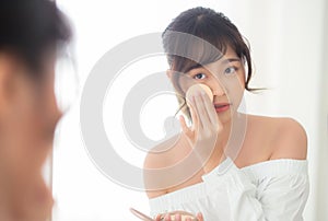 Portrait beautiful young asian woman applying powder puff at cheek makeup of cosmetic looking mirror