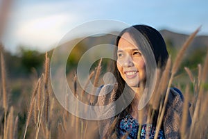 Portrait of beautiful young Asian woman enjoying nature on grass meadow at sunrise