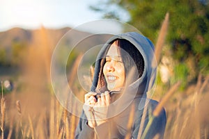 Portrait of beautiful young Asian woman enjoying nature on grass meadow at sunrise