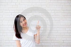 Portrait of beautiful young asian woman happiness standing finger pointing something on gray cement texture