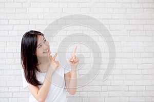 Portrait of beautiful young asian woman happiness standing finger pointing something on gray cement texture background