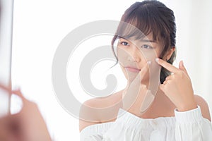 Portrait beautiful young asian woman looking the mirror is a acne, zit treatment photo