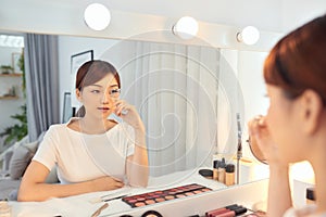 Portrait of beautiful young Asian woman looking at the mirror using eyelash curler