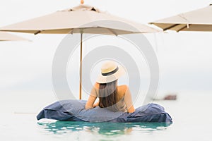 Portrait beautiful young asian woman relax in luxury outdoor swimming pool in hotel resort nearly beach sea ocean