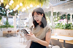 Portrait beautiful young asian woman with smart mobile phone in cafeteria at shopping mall