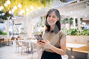 Portrait beautiful young asian woman with smart mobile phone in cafeteria at shopping mall